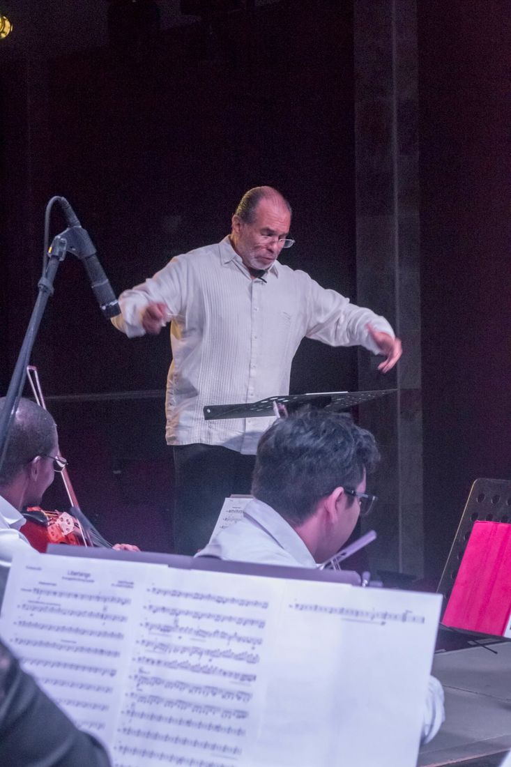 Mario Monroy dirige a la orquesta, con las partituras en primer plano